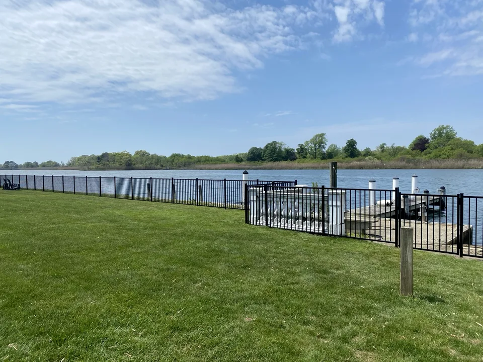 Four-foot black aluminum waterfront fence extending beside a dock in East Islip, New York.
