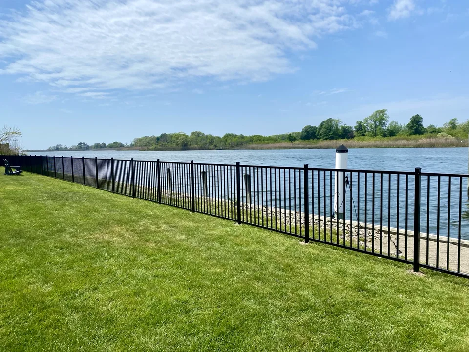 Long run of four-foot black aluminum fence following the East Islip, New York waterfront.