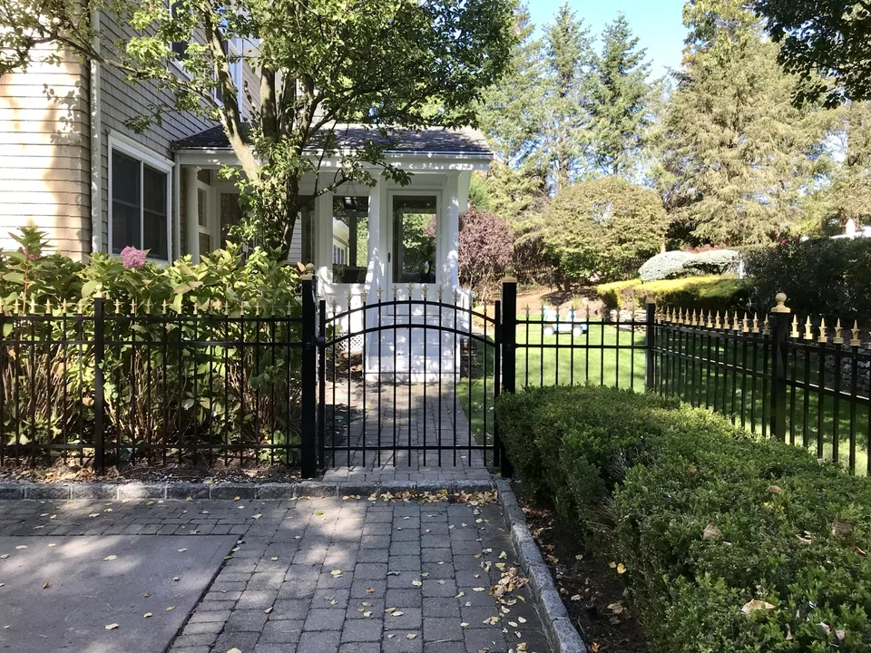 Four-foot black aluminum estate fence with gold finials, gold post caps, and an arched walk gate in Port Jefferson, New York.