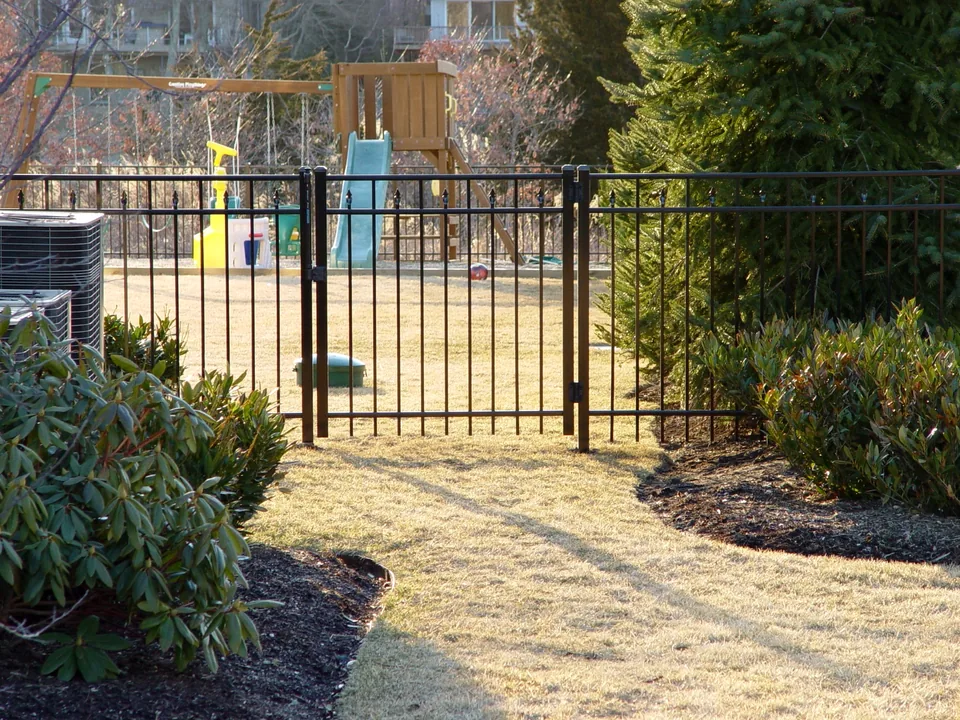 Four-foot black aluminum walk gate and adjoining fence at a residential property in Center Moriches, New York.