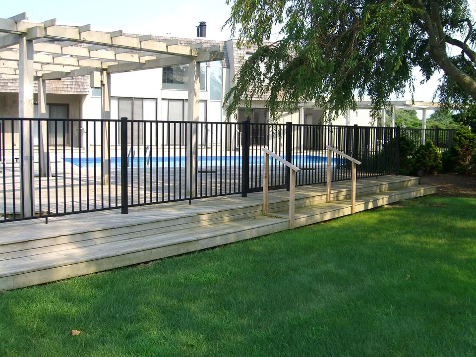 Black aluminum fence installed around the perimeter of a raised wood deck in Southampton, New York.
