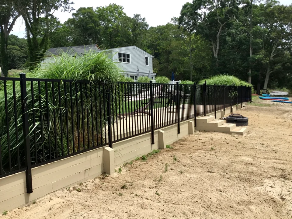 Four-foot black aluminum fence following the backyard property line in Mattituck, New York.
