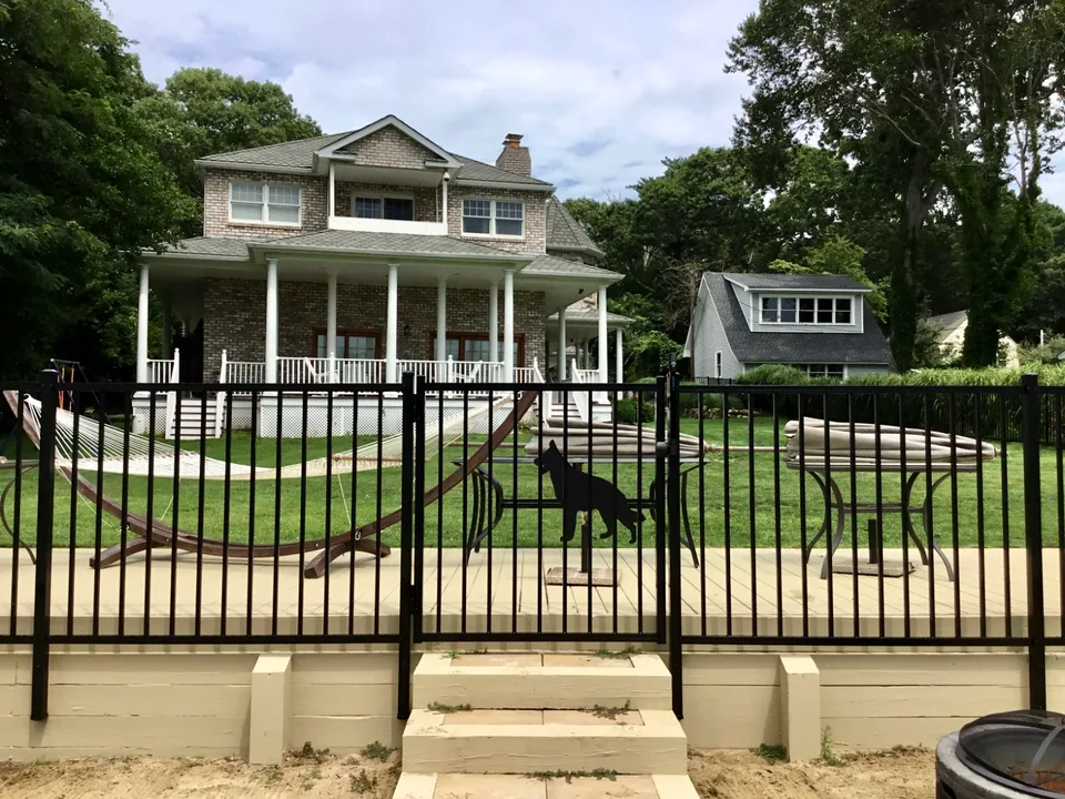 Four-foot black aluminum fence and gate beside a raised patio area in Mattituck, New York.
