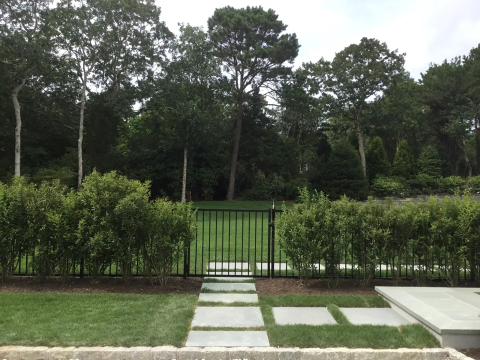 Black aluminum walk gate within a four-foot perimeter fence in Southampton, New York.