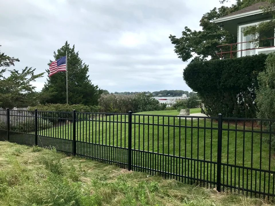 Four-foot black aluminum fence with puppy pickets across a landscaped Sag Harbor, New York property with water visible beyond.