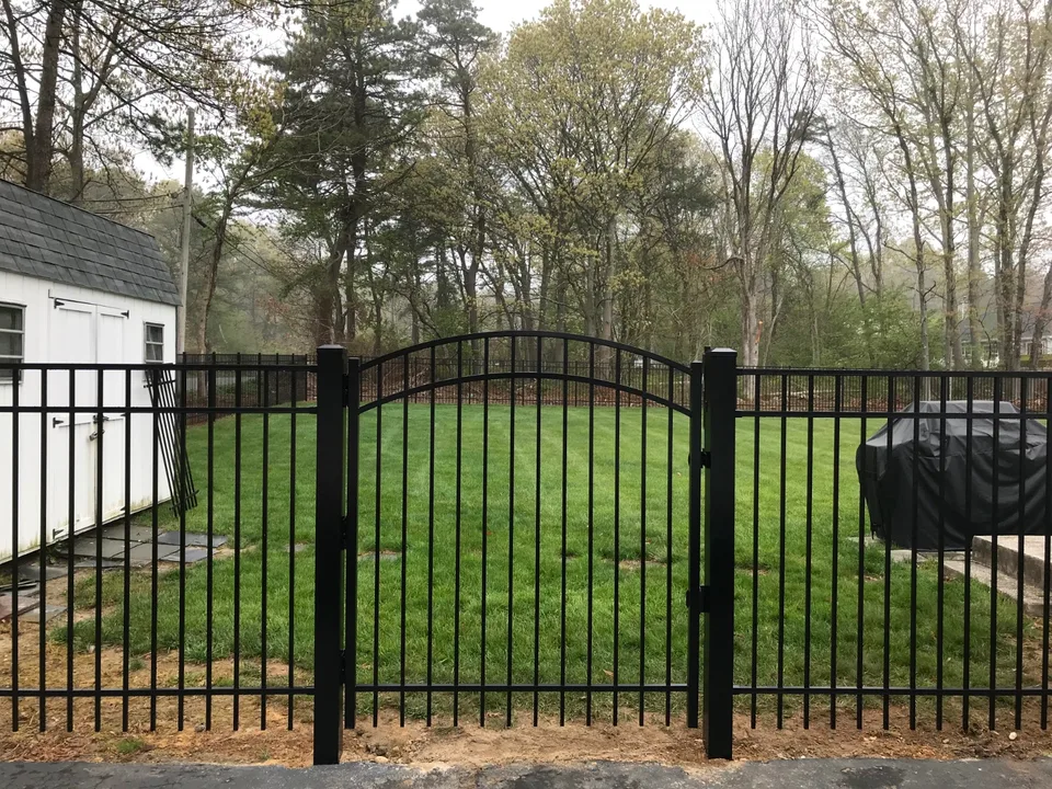 Centered arched black aluminum walk gate within a five-foot Style 202 fence in Bellport, New York.