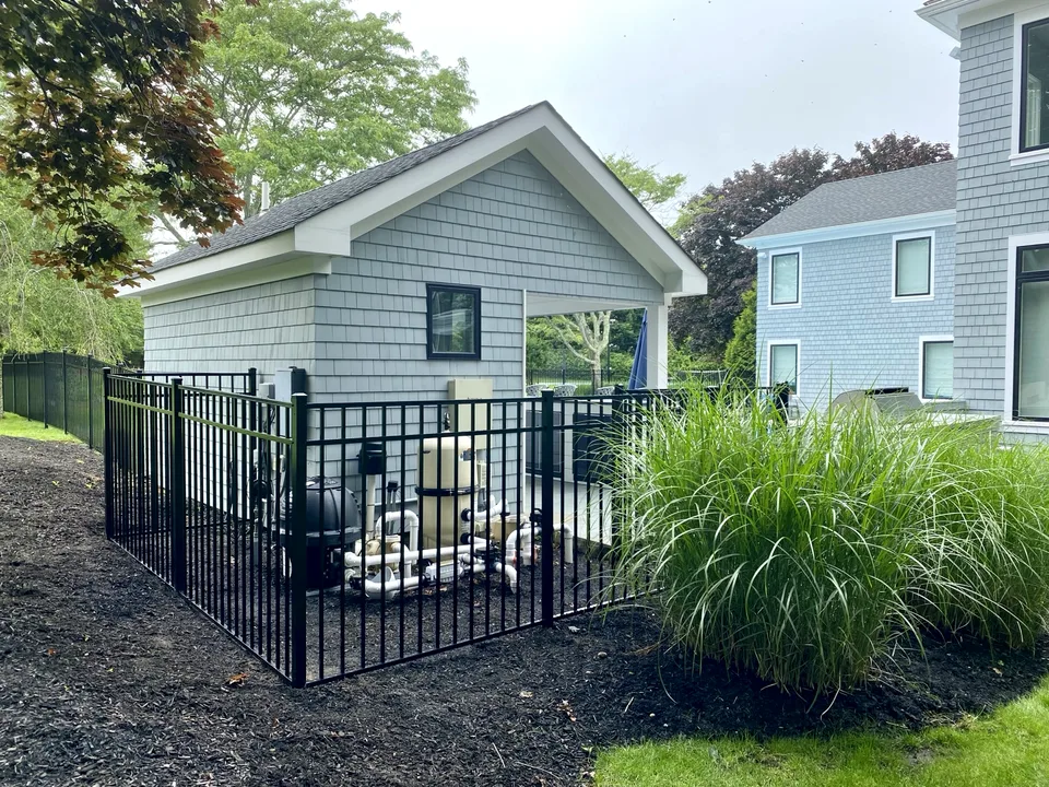 Black aluminum fence and gate enclosing a pool-equipment area at a Remsenburg, New York residence.