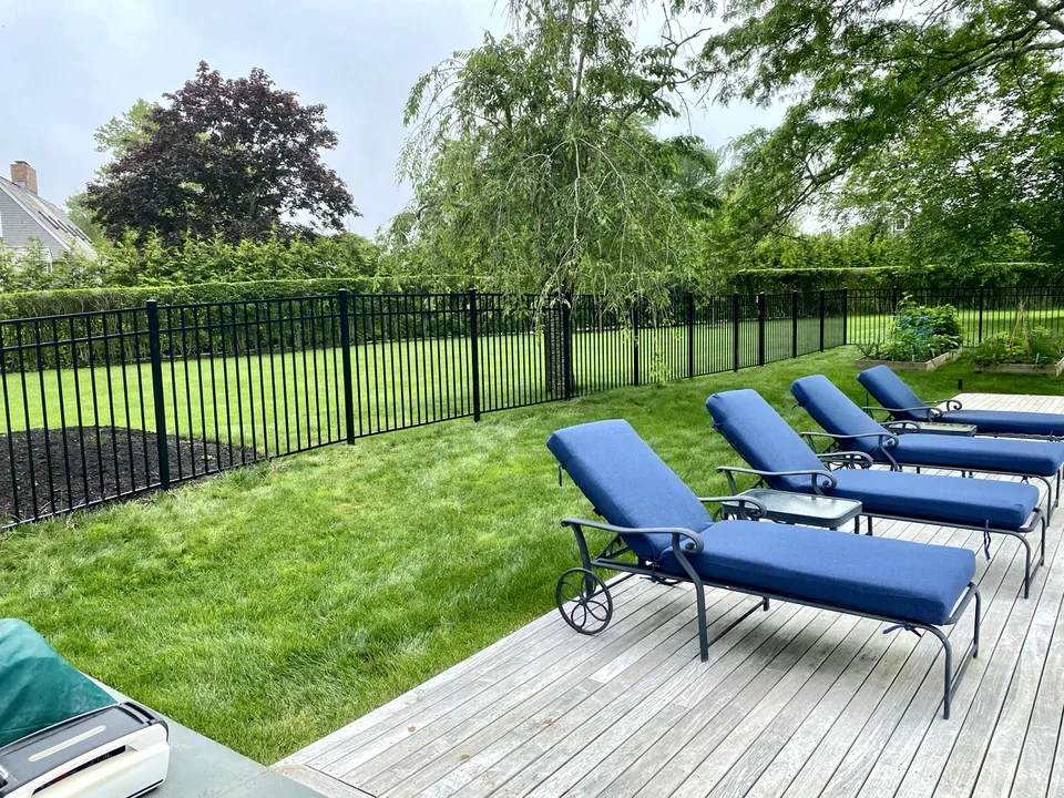 Long run of fifty-four-inch black Style 202 aluminum fence defining landscaped garden and yard areas in Remsenburg, New York.