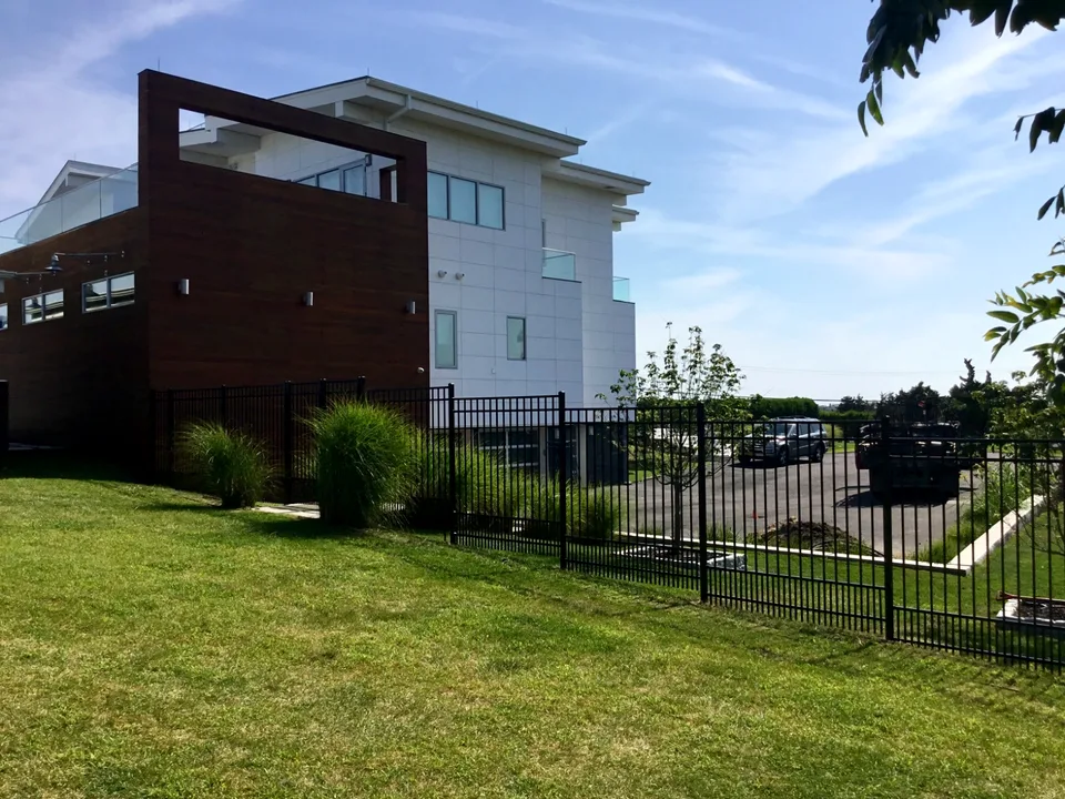 Six-foot black aluminum residential fence across a sloped Westhampton, New York property.