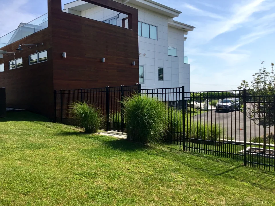 Six-foot black aluminum fence installed in stepped sections across a Westhampton, New York grade.