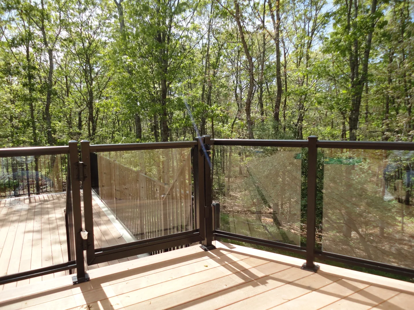 Custom aluminum-framed glass gate and corner transition on the elevated wood deck in Southampton, New York
