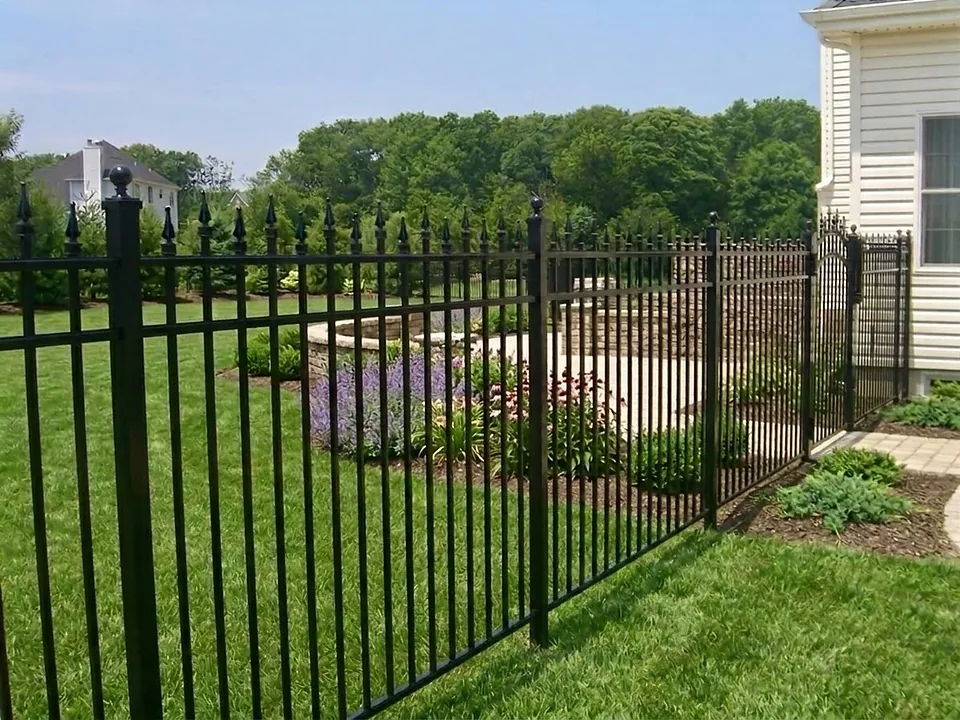 Fifty-seven-inch black Onguard aluminum fence with spear-top pickets, ball-capped posts and an arched gate, running along a landscaped lawn beside a shingled home in Miller Place, New York