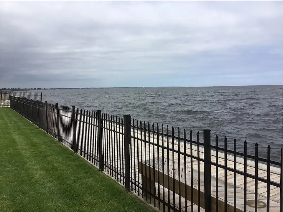 Black aluminum spear-top fence running along a new bulkhead walkway at a bay-front property in West Islip, New York