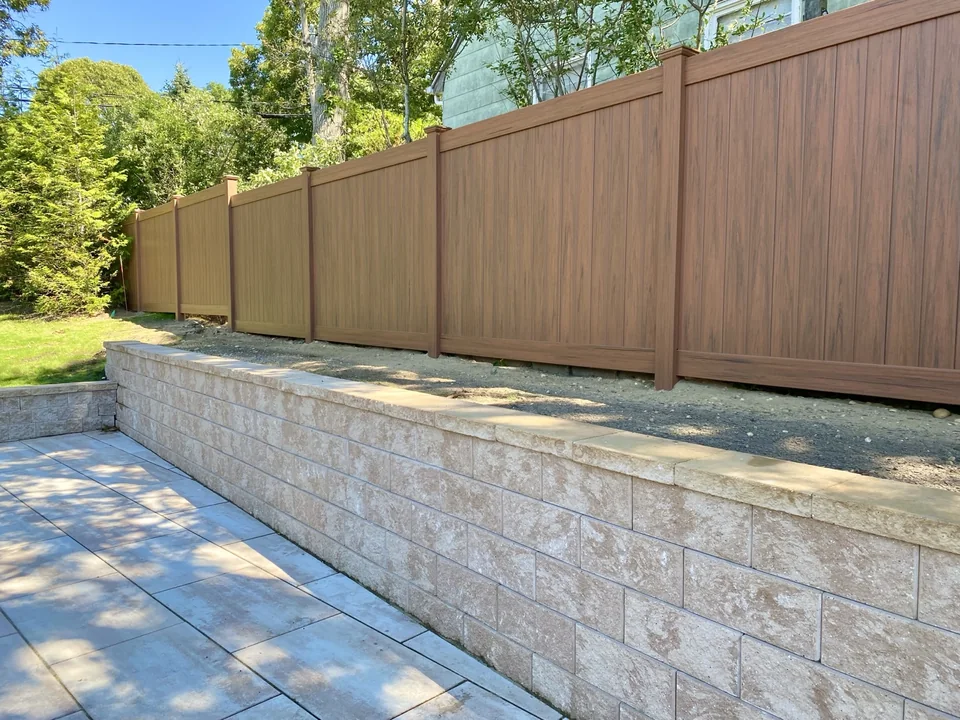 Angled view of the cedargrain PVC privacy fence running above the Sag Harbor retaining wall