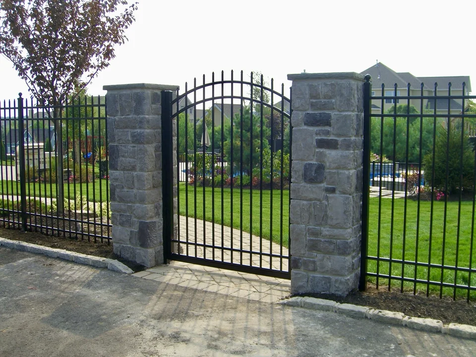 Arched black aluminum gate aligned between masonry columns in Miller Place, New York