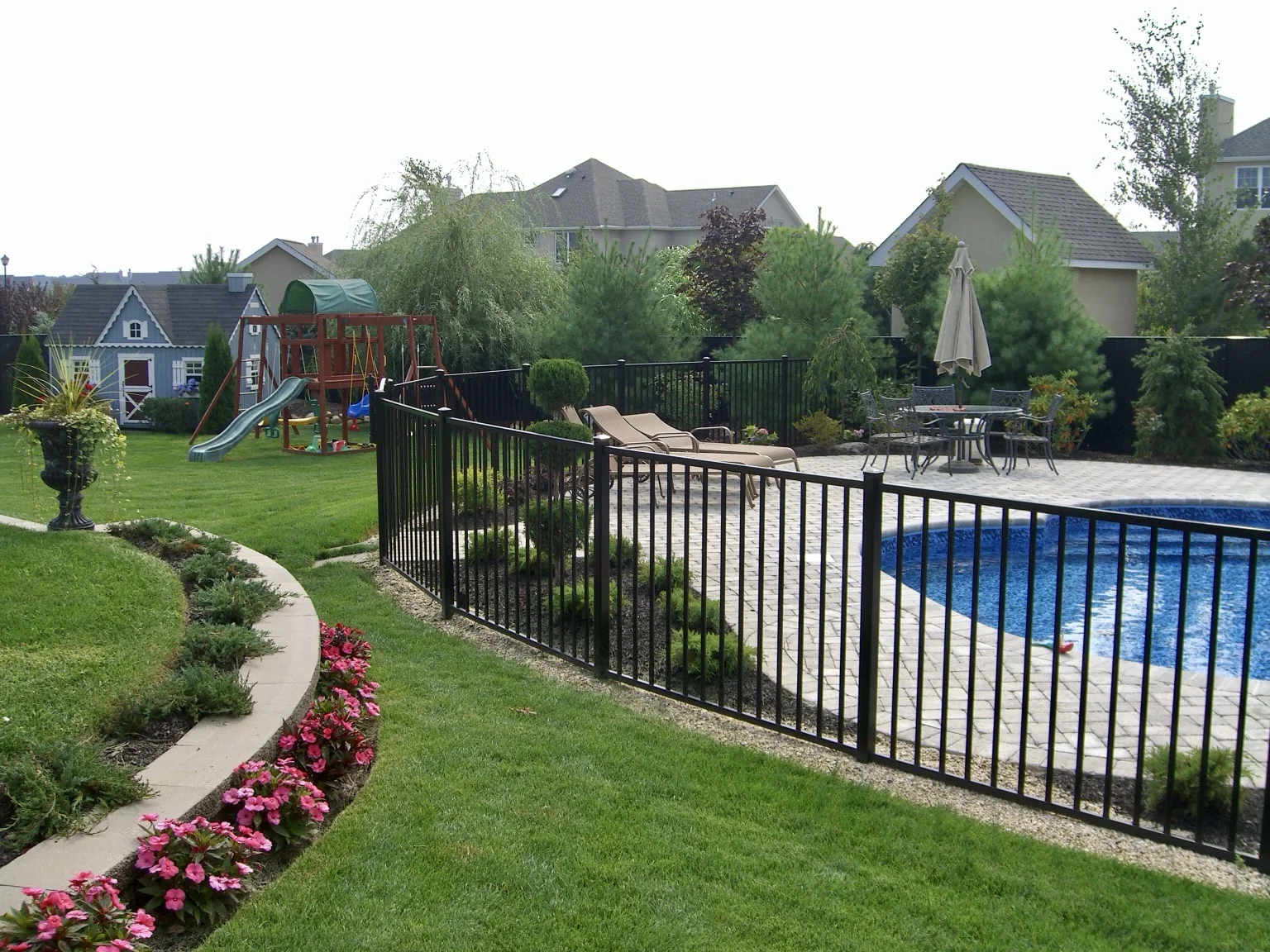Soft-radius black aluminum pool fence following the landscaped pool area in Miller Place, New York