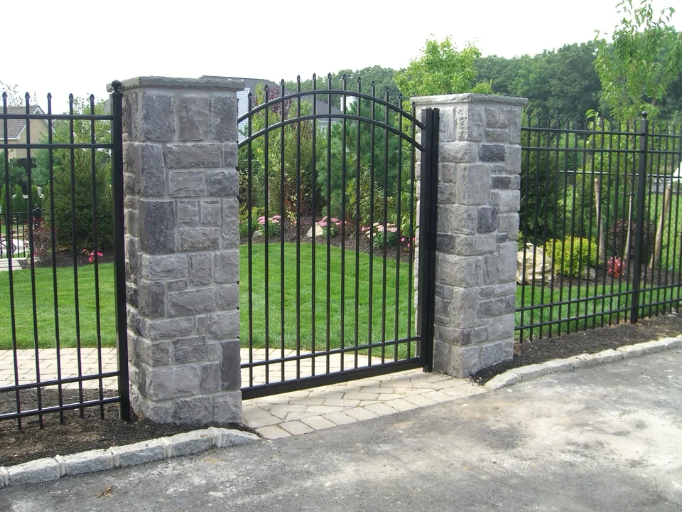 Black aluminum pool fence and gate within a landscaped Miller Place backyard