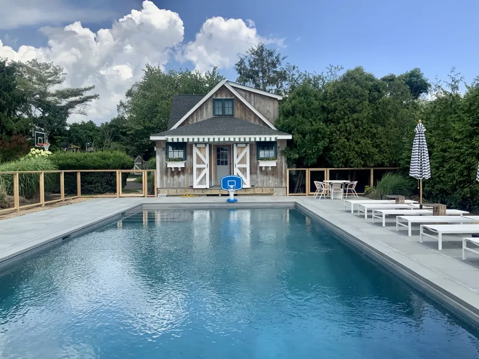 Custom cedar framed wire pool fence beside a pool house in Westhampton, New York