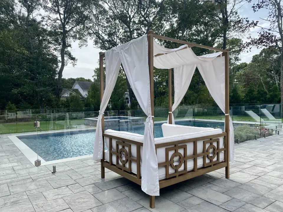 Close view of a frameless glass pool fence and luxury daybed in Remsenburg, New York.