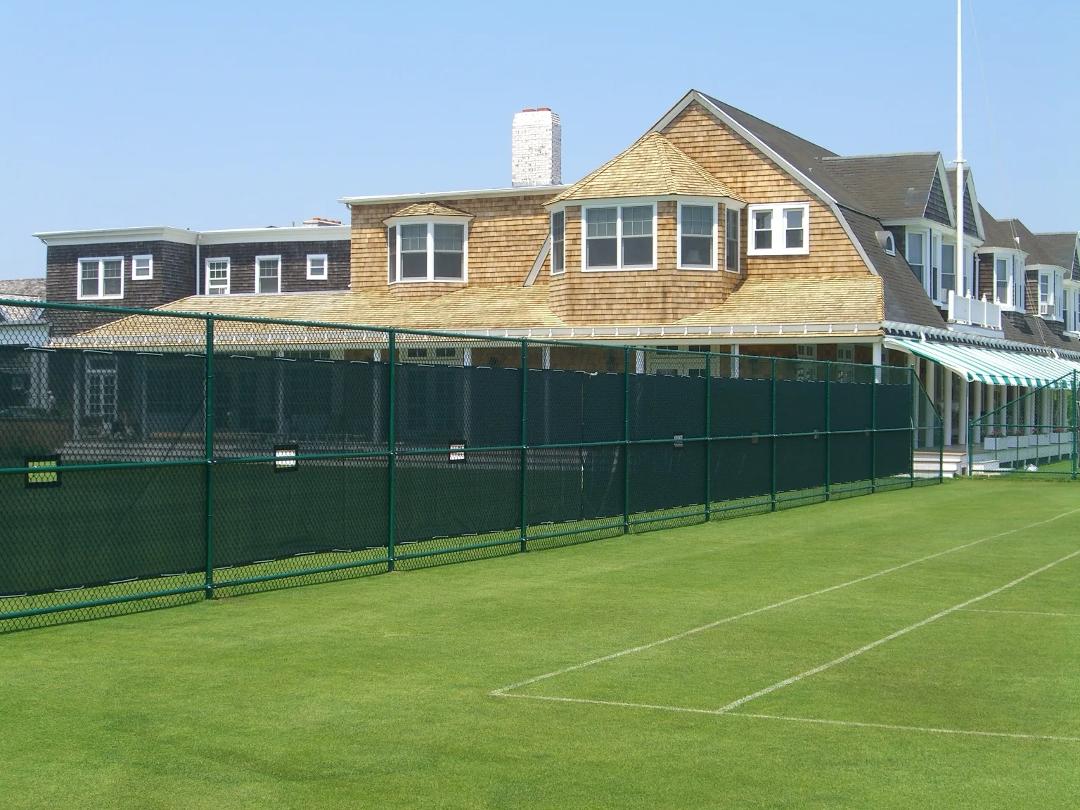 Tall green chain link tennis court enclosure at a private tennis club in Southampton, New York