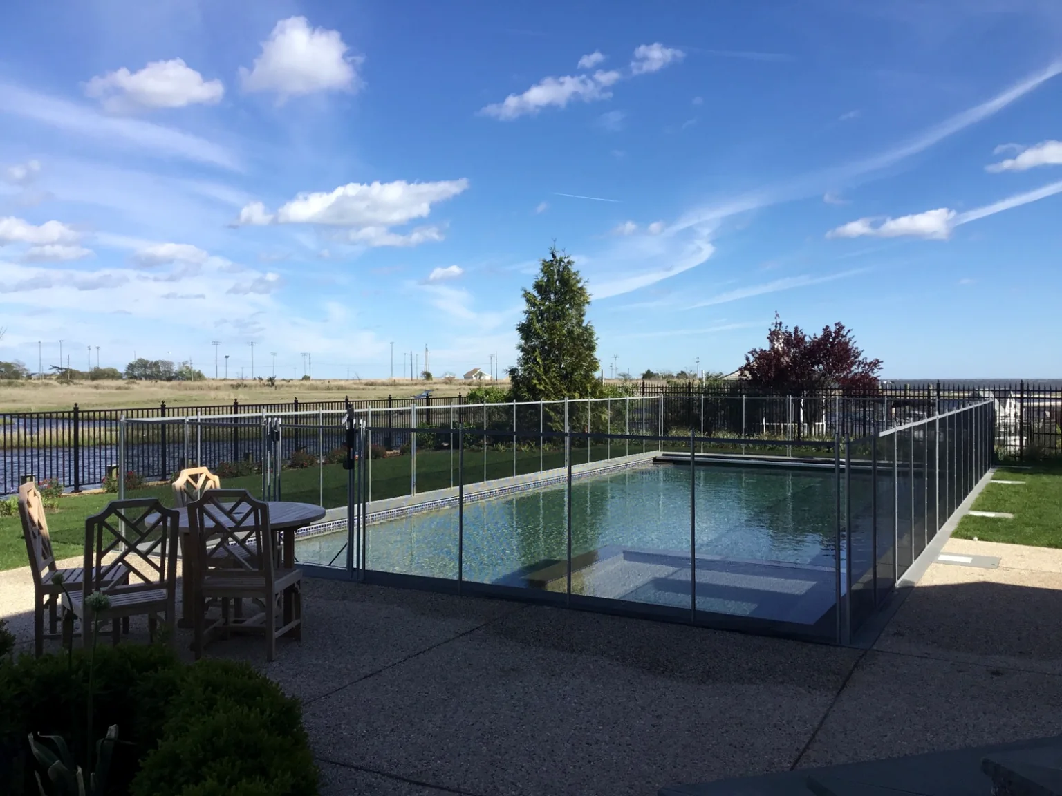 Guardian Vanishing removable mesh pool fence preserving the open waterfront view at a pool in The Moorings, East Islip, New York