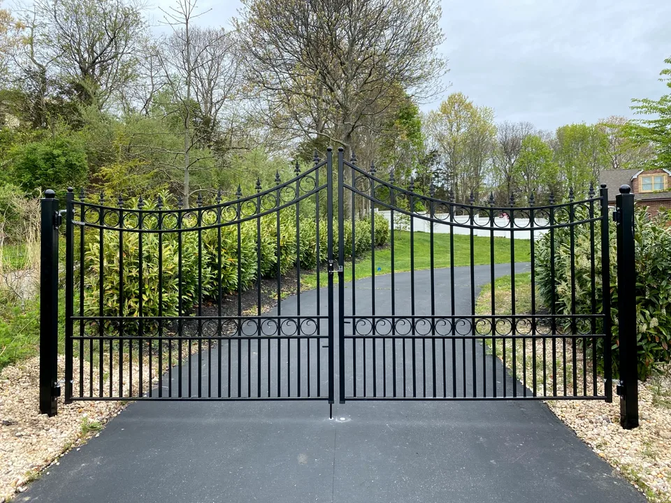 Closed black ornamental steel double-drive entrance gate viewed from inside the property in Calverton, New York.
