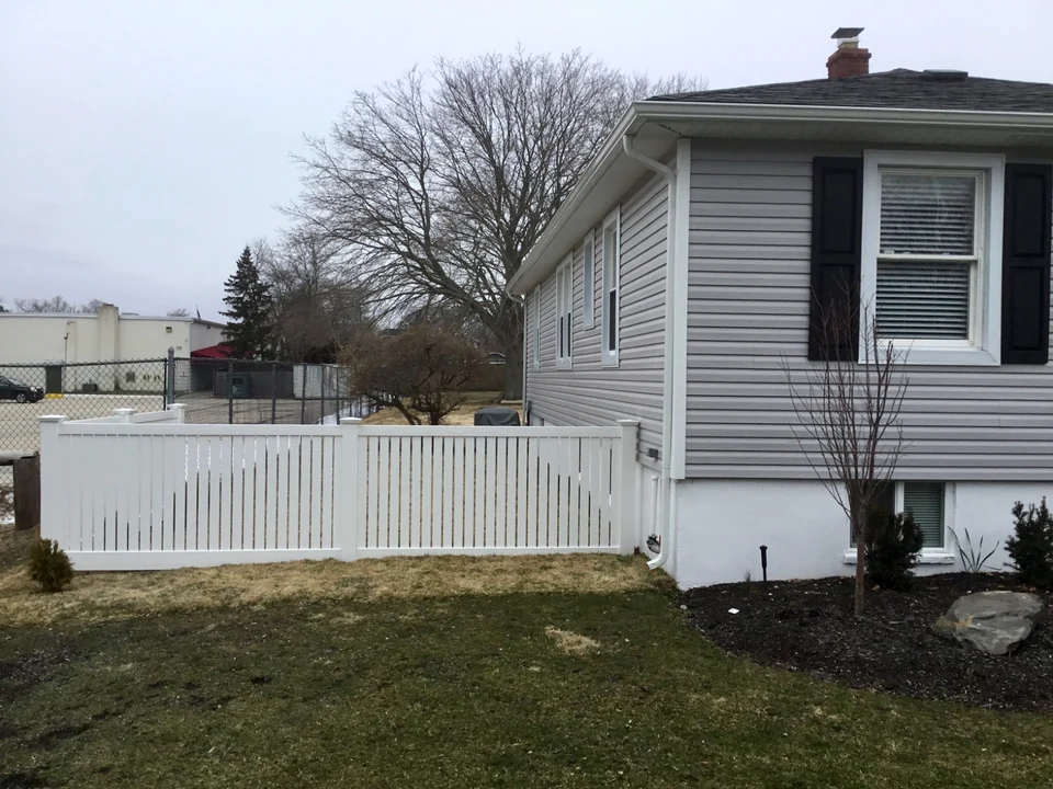 White four-foot semi-privacy PVC fence enclosing a side yard beside a gray home in Patchogue, New York
