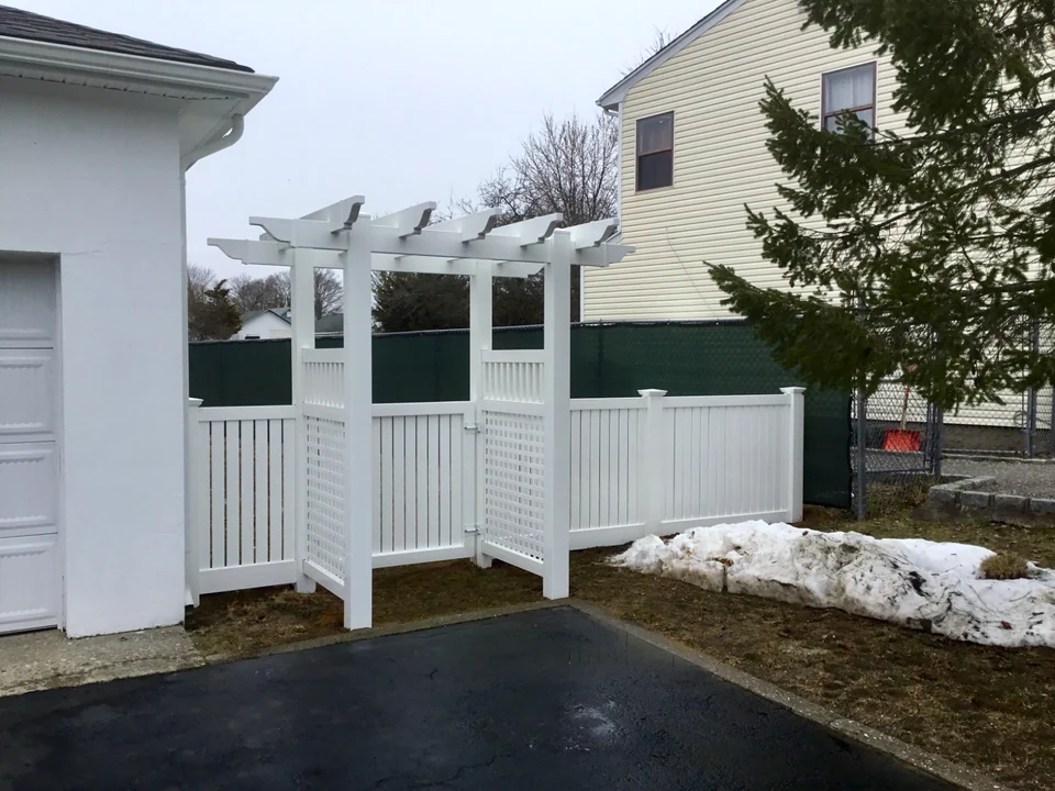 Angled view of a white PVC arbor walk gate integrated with New Jersey semi-privacy fencing in Patchogue, New York