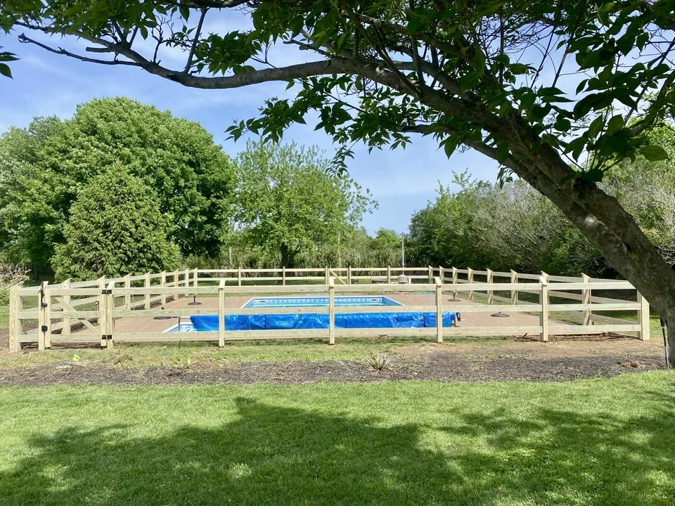 Pool-code-compliant pressure-treated post and rail wire fence in Aquebogue, New York