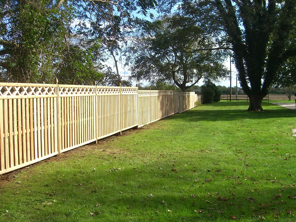 Six-foot shadow box cedar fence with an X-lattice topper on pressure-treated Gothic-top posts, running along a lawn in Southampton, New York