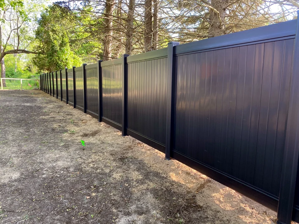 Perspective view down a long run of six-foot Blackline black PVC privacy fencing in Southold, New York.