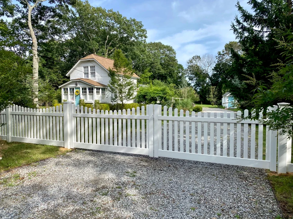 Four-foot white PVC picket double driveway gate and matching fence in Speonk, New York.