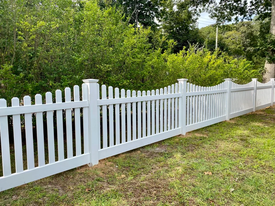 Angled run of four-foot white PVC picket fence connected to the Speonk driveway gate.