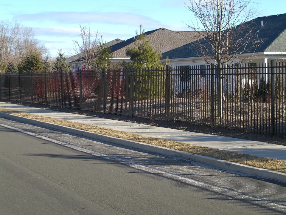 Street view of the six-foot black Ultra UAS 100 commercial aluminum fence at a Stony Brook residential community.