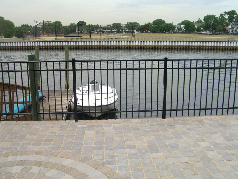 Black aluminum waterfront fence with a boat and canal beyond at a Seaford home