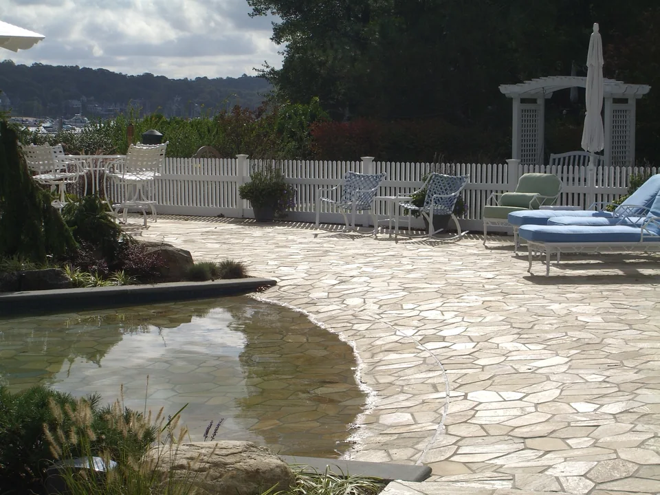 White PVC picket fencing around a landscaped pool patio in Centerport, New York